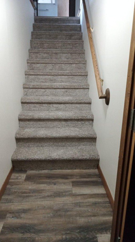 Carpeted stairs meeting LVP at the landing