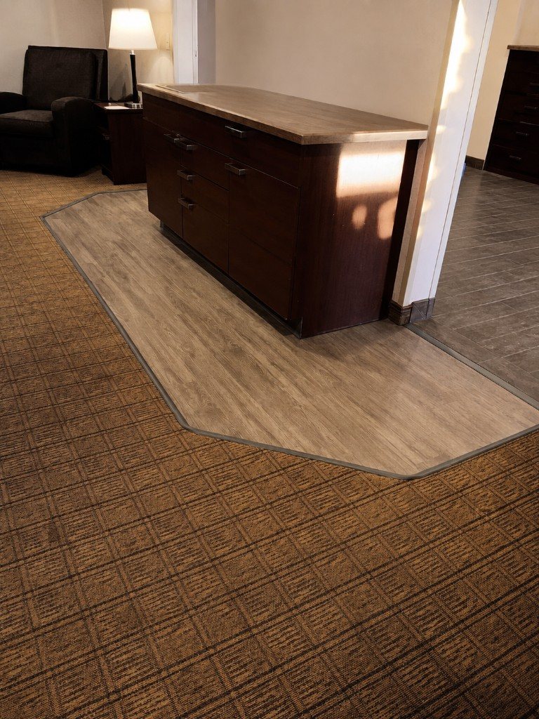 Custom LVP inset cut into commercial carpet around a cabinet