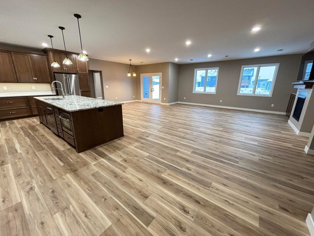 Wide plank LVP through a kitchen and living room, installed by Barefoot Flooring in Grand Forks