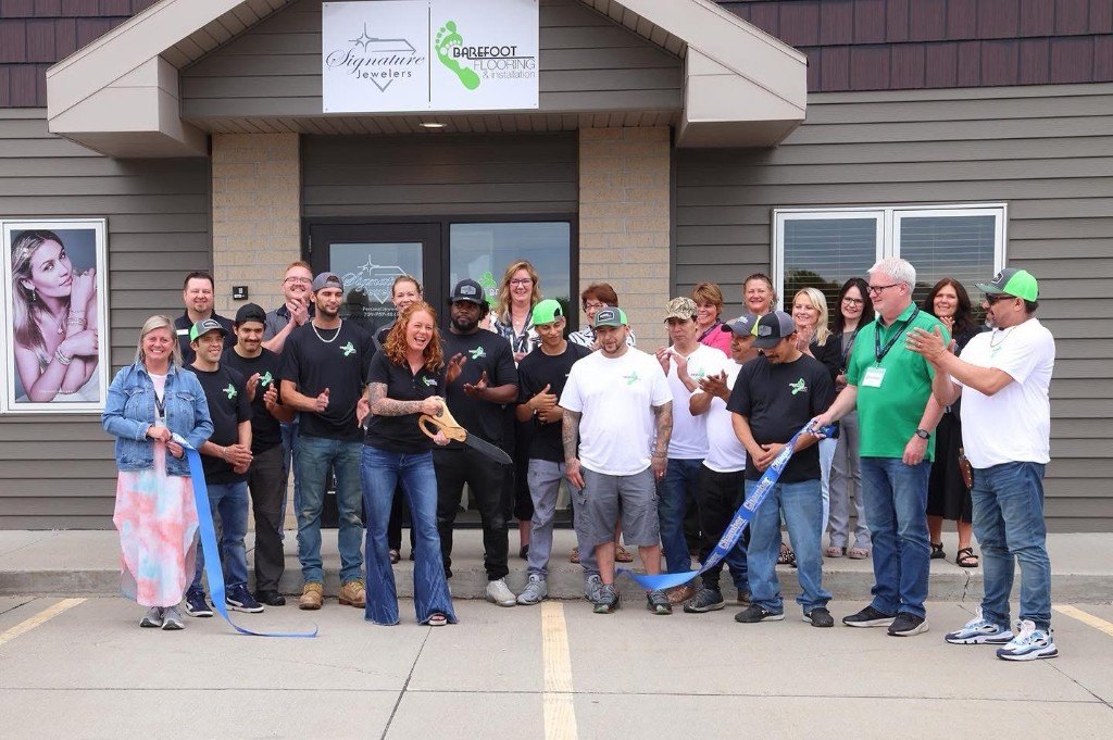 Christy Merkel and the Barefoot Flooring crew cutting the Chamber ribbon at the Grand Forks showroom opening
